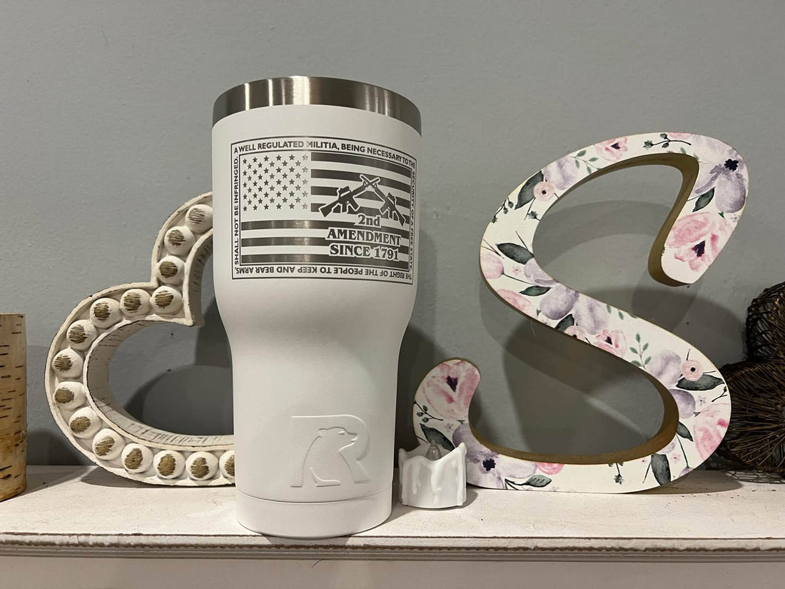 A white tumbler laser engraved with a flag and Second Amendment design