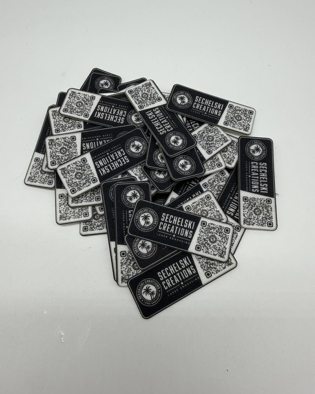 A finished batch of black custom logo patches with metallic designs